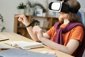 A teenager using a VR headset for interactive learning at home with educational materials on a wooden table.